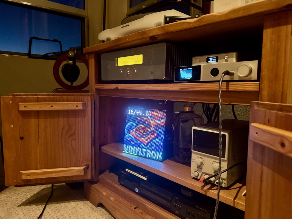 Vinyltron glowing inside a media cabinet alongside high-end audio equipment